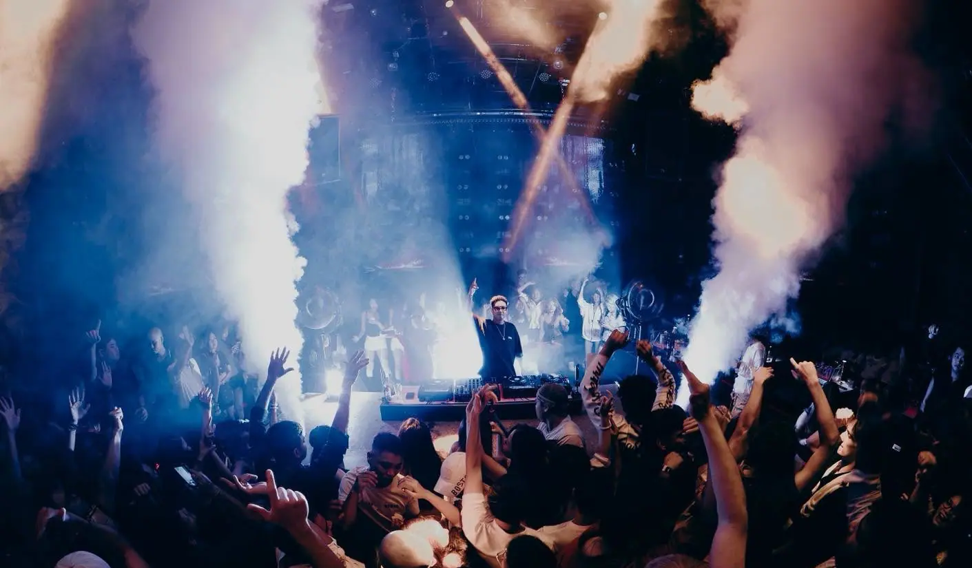 DJ đứng giữa hai cột khói CO2 xanh, tia đèn bắt chéo phía sau tại 1900 Le Théâtre
